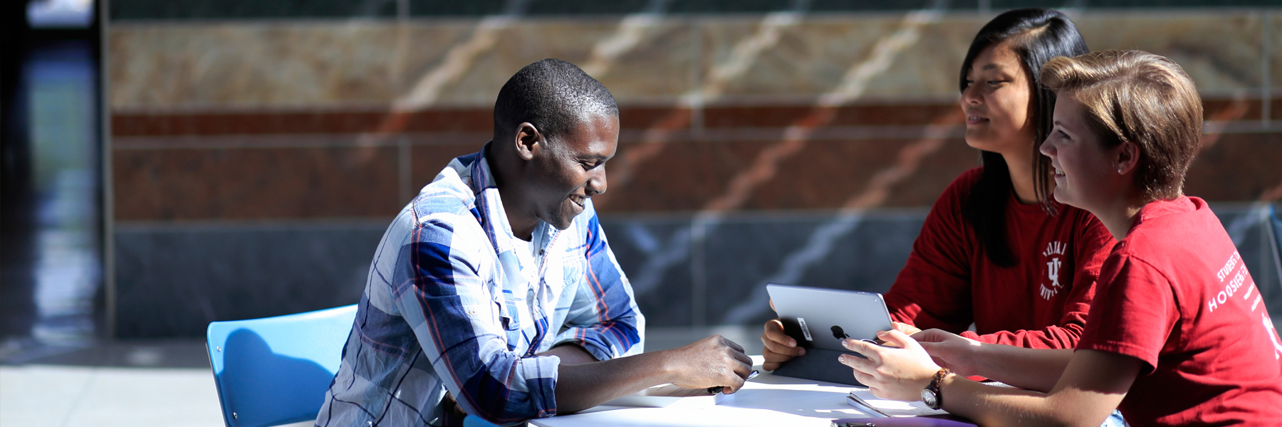 A group of students sit and talk in the sunshine.